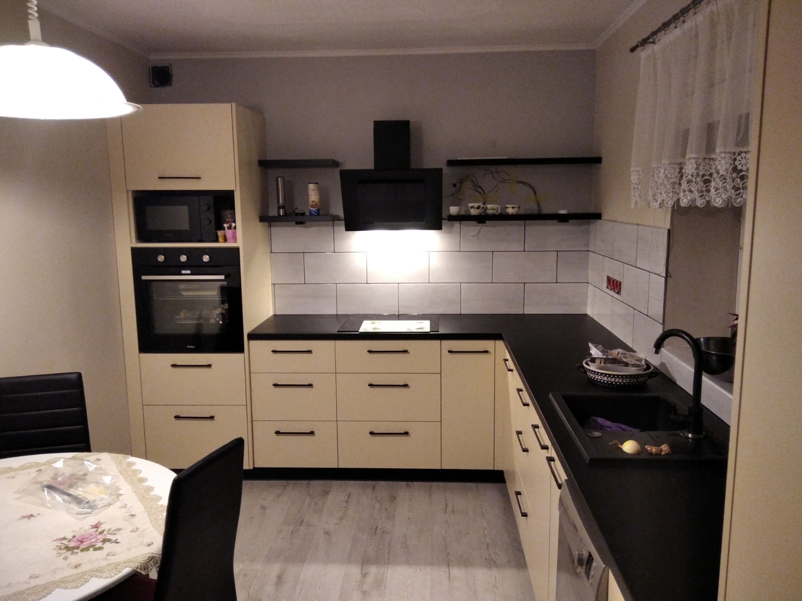 Jasne meble kuchenne z czarnym blatem i zlewem.